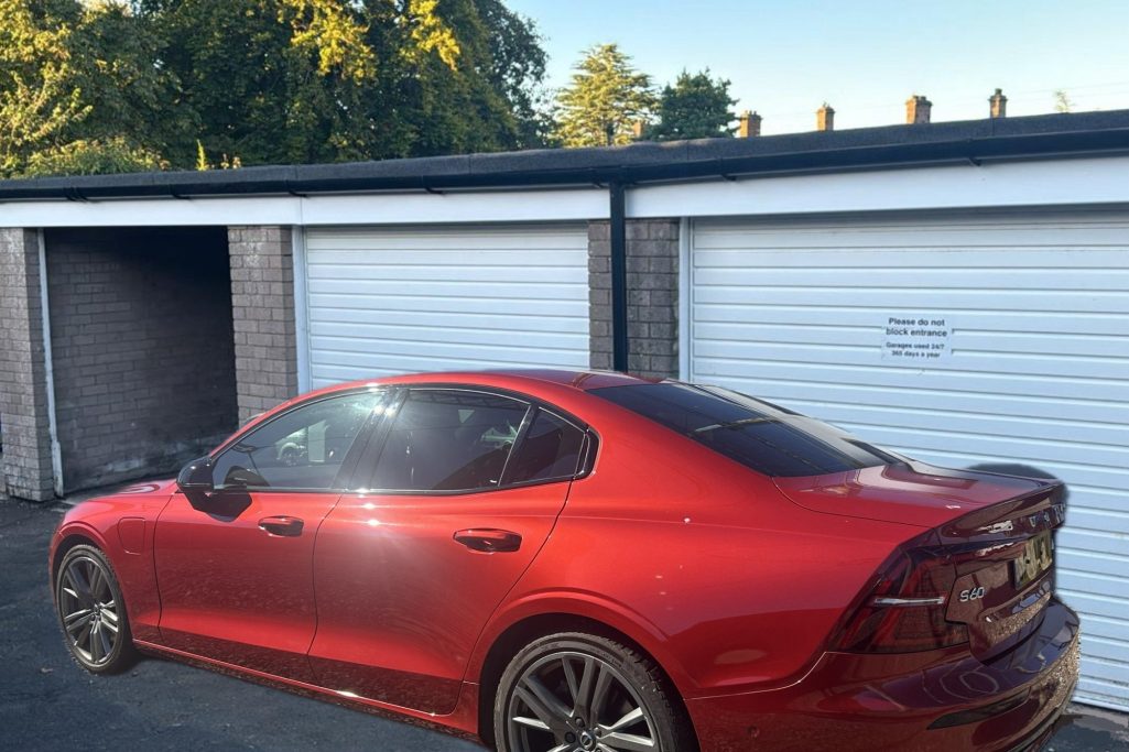 car beside a pair of lock up garages