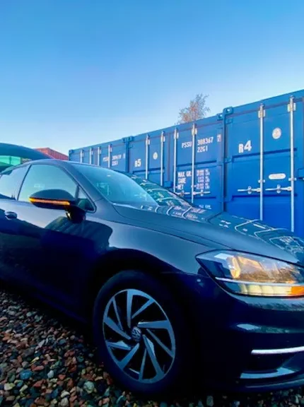 a car parked outside some shipping containers used for self storage