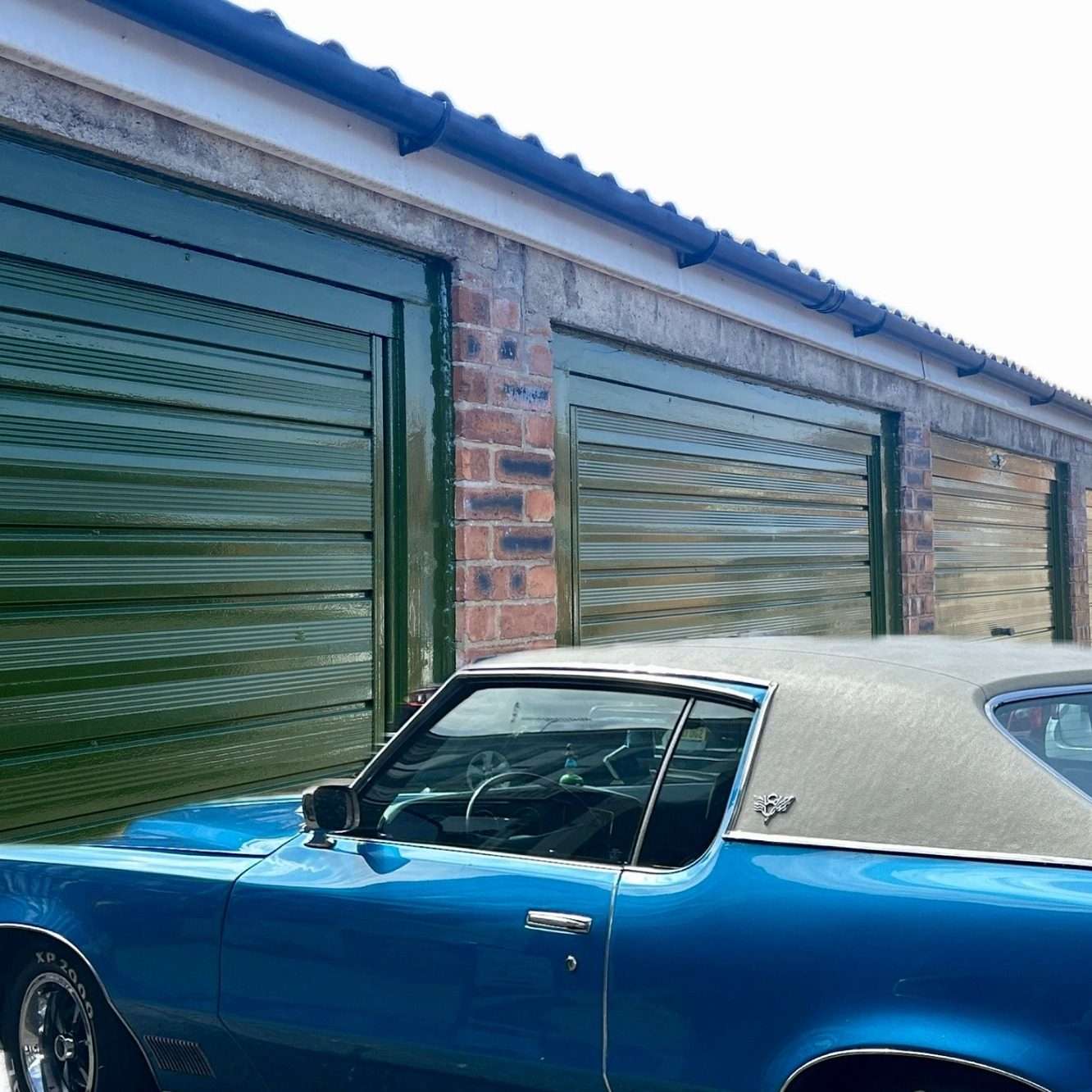 a vintage car next to a lock up garage